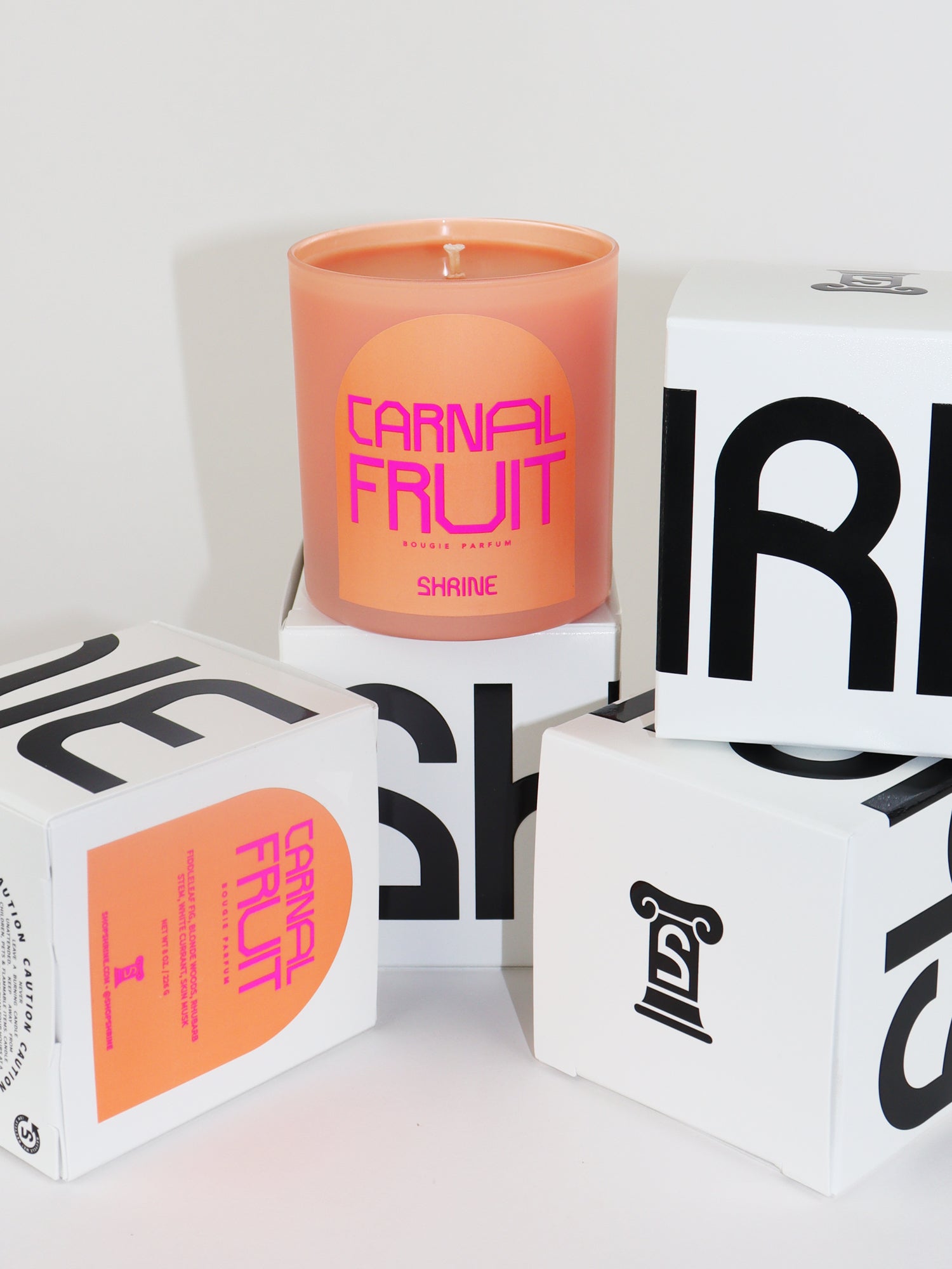 shrine carnal fruit monochromatic peach candle with neon pink text design in a neon pink logo label black and white candle box shop shrine shopshrine